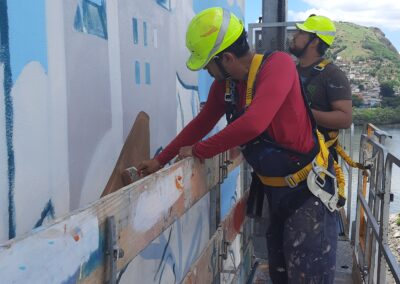 Dois homens jovens pintando a empena do edifício Humberto Gobbi.