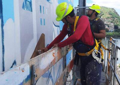Dois homens jovens pintando a empena do edifício Humberto Gobbi.