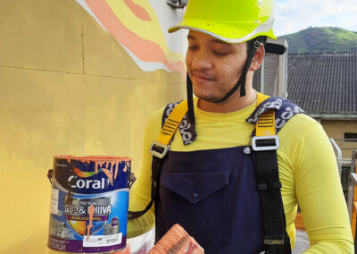 Homem jovem segurando uma lata de tinta ao lado da parede pintada.