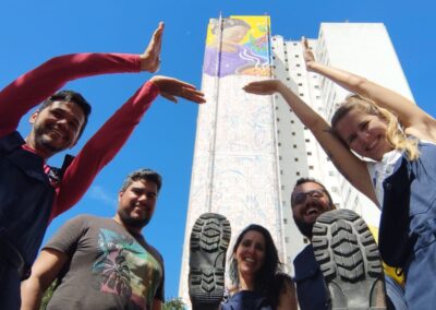 Foto dos artistas (três rapazes e duas moças) em frente em frente ao mural recém iniciado.
